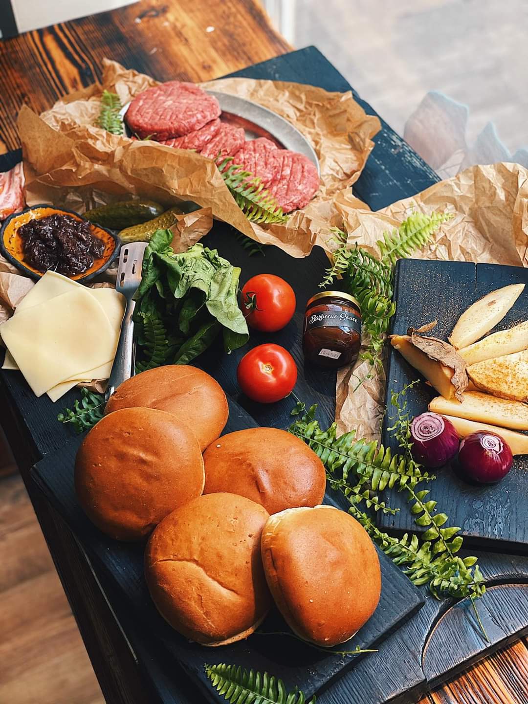 Beef burger preparation with patties, buns, cheese, tomatoes and onions